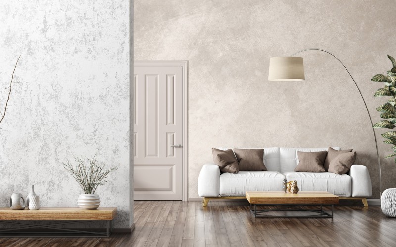 Modernes Wohnzimmer mit weißem Sofa, braunen Kissen, Holzboden, großer Zimmerpflanze und dekorativer Wandgestaltung